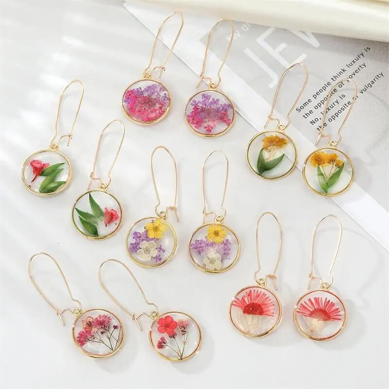 collection de boucles d'oreilles couleur or en fleurs séchées dans de la résine